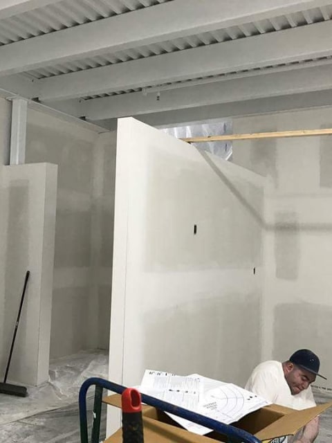 a person preparing drywall for paint